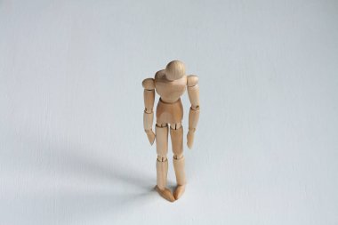 Beyaz arka planda bükülmüş omuzları olan tahta bir manken.