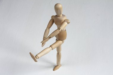 Beyaz arka plan üzerinde egzersiz yapan ahşap bir manken.