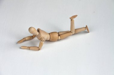 Beyaz arka planda yatan ve eğlenen tahta bir manken.