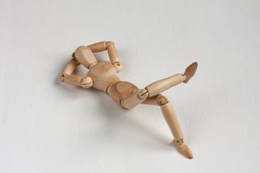 Beyaz arka planda yatan ve eğlenen tahta bir manken.