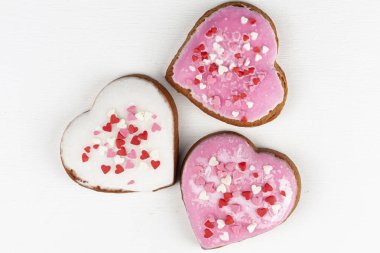 Beyaz arkaplanda iki pembe ve bir beyaz kalp şeklinde zencefilli ekmek.