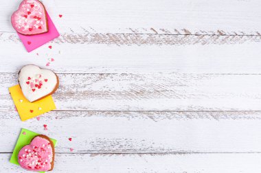 Pembe ve beyaz kalp şeklinde küçük kırmızı, pembe ve beyaz kalpler beyaz ahşap arka plandaki çıkartmalarda.