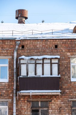 Çatısı karla kaplı bir apartmanın balkonuna.