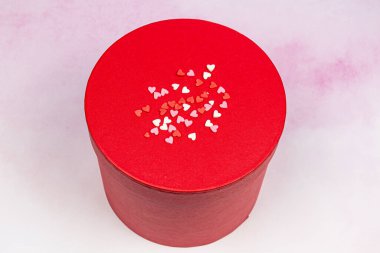 suluboya arka planda beyaz, pembe ve kırmızı kalpleri olan yuvarlak, güzel bir hediye kutusu.