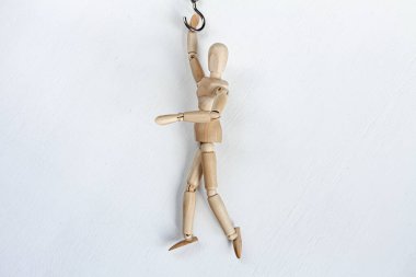 Beyaz arka planda asılı duran ahşap bir manken.