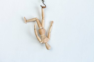 Beyaz arka planda asılı duran ahşap bir manken.