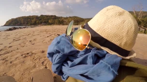 Шляпа и солнцезащитные очки на куче одежды. Концепция пляжного отдыха — стоковое видео