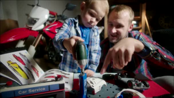 Отец помогает сыну игрушечной электрической отверткой — стоковое видео