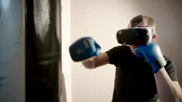 Caixas de homem jovem no ginásio usando óculos VR e saco de perfuração — Vídeo de Stock