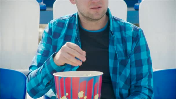 Jonge man eten popcorn in het stadion — Stockvideo