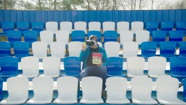 Guy in VR glasses talking the phone at the stadium — Stock Video