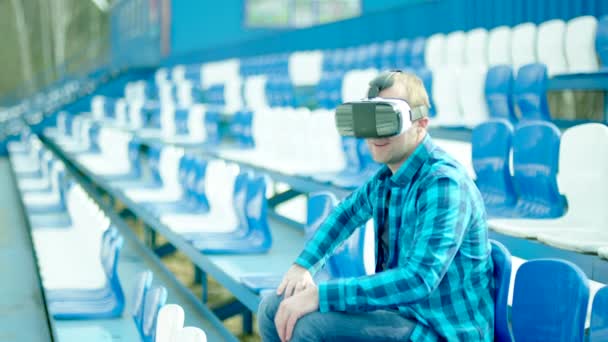 Joven en gafas VR animando a un equipo en la tribuna — Vídeos de Stock