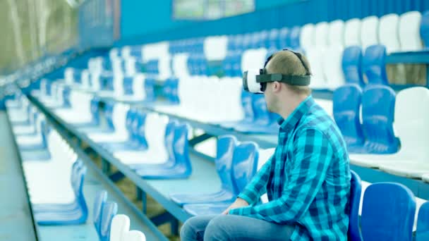 Tipo molesto en gafas VR sentado en la tribuna — Vídeos de Stock