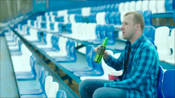 Chico bebiendo de la botella en el estadio tribuna — Vídeo de stock