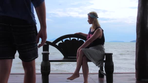 Junge und Mädchen sitzen auf einer Bank am Meer — Stockvideo