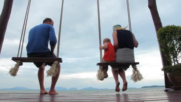 Vater und Mutter mit ihrem Sohn auf einer Schaukel am Meer — Stockvideo