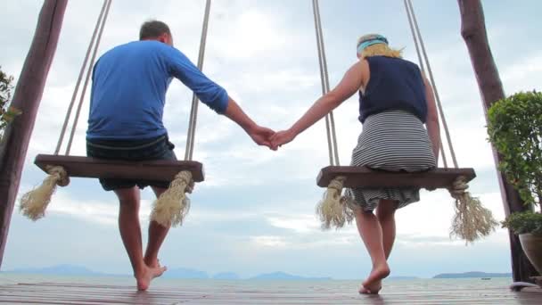 Муж и жена качаются на качелях на берегу — стоковое видео