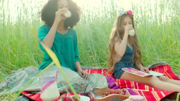 Девушки сидят в поле и пьют молоко — стоковое видео