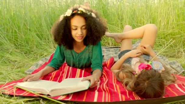 Young girls lying on cover and reading — Stockvideo