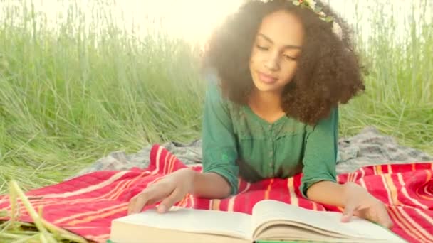 Young girl lying on cover and reading — Stok video