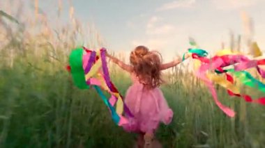 Young girl running with colored ribbons in her hands through the wheat field