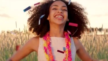 Young girl enjoying confetti rain in the wheat field during sunset