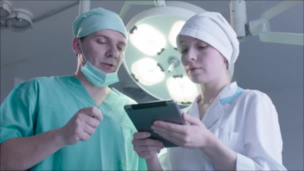 Tres doctores usando una tableta en una oficina brillante — Vídeo de stock