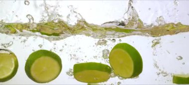 Yavaş çekim limonları suya sıçrar, canlı yeşil dilimler, ferahlatıcı damlacıklar, ticari çekim