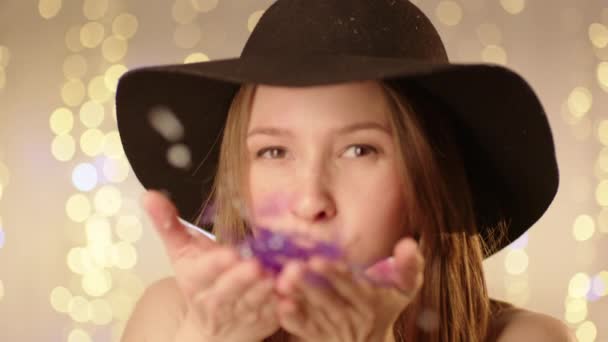 Sorrindo mulher soprando Confetti para câmera — Vídeo de Stock