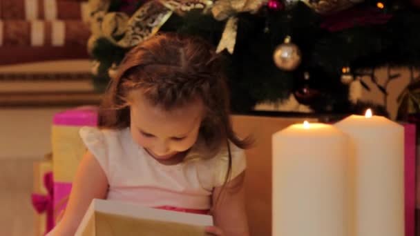 Meisje spelen met speelgoed door kerstboom — Stockvideo