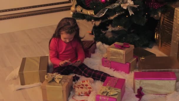 Mädchen spielt mit Smartphone am Weihnachtsbaum — Stockvideo