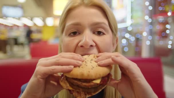 Улыбающаяся женщина ест бургер — стоковое видео