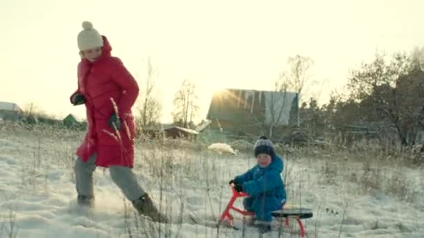 Έλκηθρο τράβηγμα μητέρας με τον γιο της χαμογελώντας το χειμώνα — Αρχείο Βίντεο