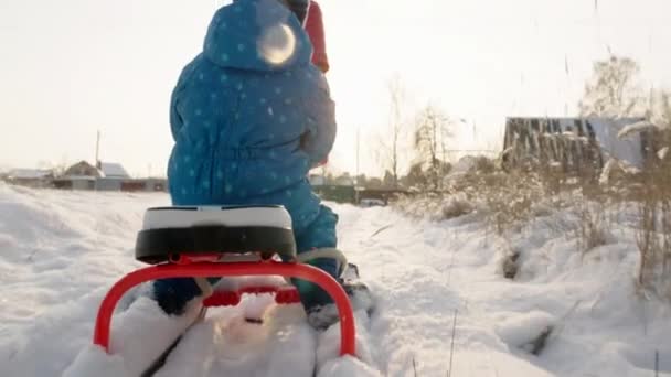 Madre e hijo montando el trineo en el día de invierno — Vídeos de Stock