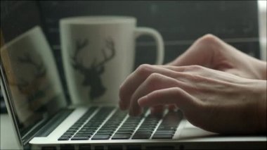 Adam içinde laptop, yakındaki ayakta kupa yazarak