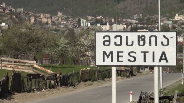 Ein Kleinbus fährt in Mestia an einem Schild vorbei. — Stockvideo