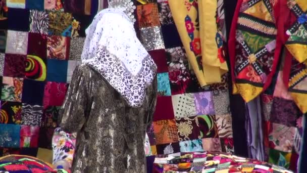 Una mujer está mirando mantas de colores en el bazar . — Vídeo de stock
