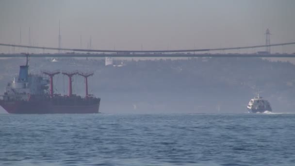 A cargo vessel sails under the Bosporus bridge. — Stock Video