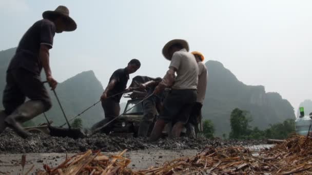 Yangshuo, China - 10 augustus, 2010: werknemers trekken een ploeg in een landelijk gebied in China, om te bouwen van een nieuwe weg in de landelijke omgeving in Yangshuo, China op 10 augustus, 2010 — 图库视频影像