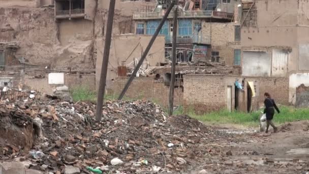 Mujer camina a casa a través de un demolido — Vídeo de stock