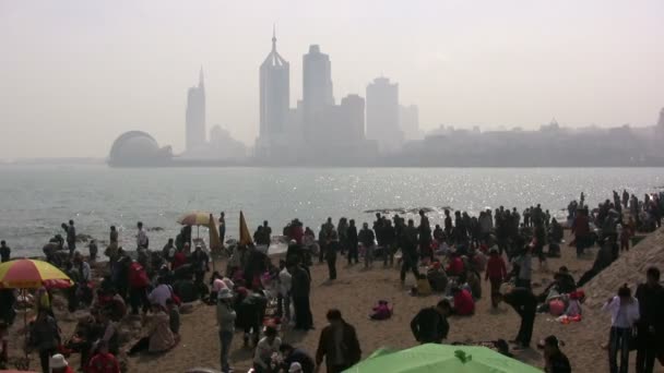 A crowded beach with the skyline of Qingdao Royalty Free Stock Video