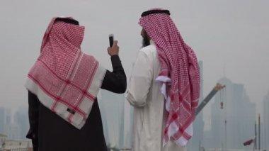 İki adam Doha siluetinin fotoğraflarını çekiyor.