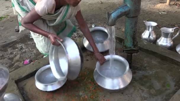 Женщины чистят миски у водяного насоса — стоковое видео