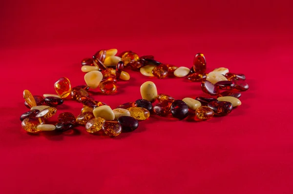 Beads of amber on a red background — Stock Photo, Image