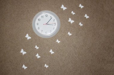 Duvardaki saat ve beyaz kelebekler.