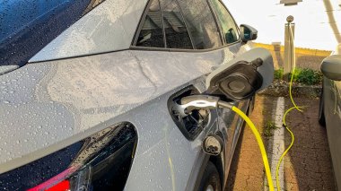 Elektrikli araba şarjı için güç kaynağı. Elektrikli araba şarj istasyonu. Şarj edilen bir elektrikli arabaya takılan güç kaynağını kapatın..