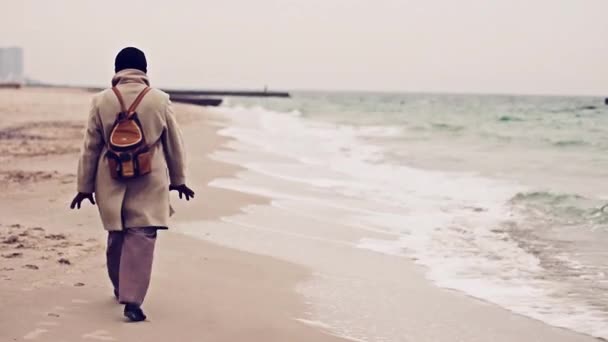Мандрівник йде уздовж краю моря взимку — стокове відео