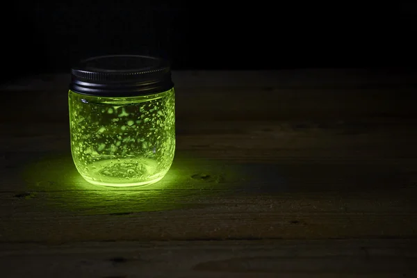 Green glowing jar on the boards — Stock Photo, Image