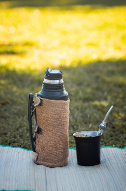 Termos ve mat kabağı parktaki çimlerin üzerinde siyah çelikten, geleneksel açık hava karışımı..