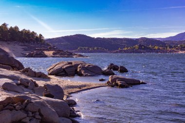 Kayalarla dolu bir göl sahilindeki dağ manzarası..